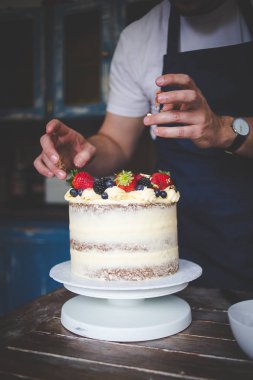 Krema ve çıplak bir pasta oluşturma ile bir havuç kek dekorasyon bir şef görüntüsünü kapatmak.