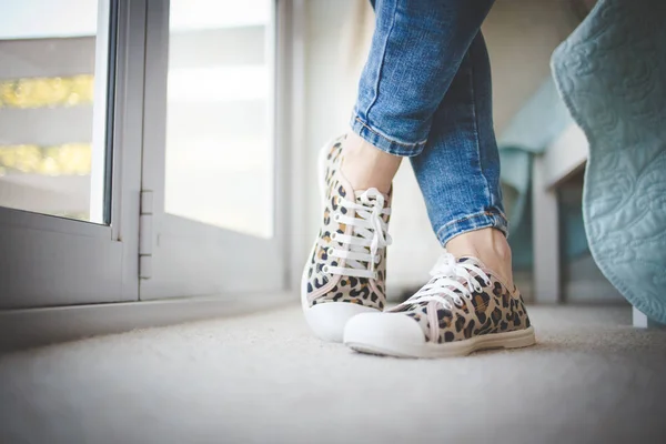 Close up image of the feet of a woman wearing sneakers and standing relaxed