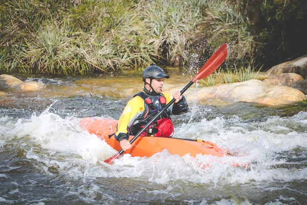 Close up image of a white water kayak paddler riding white water on a mountain river