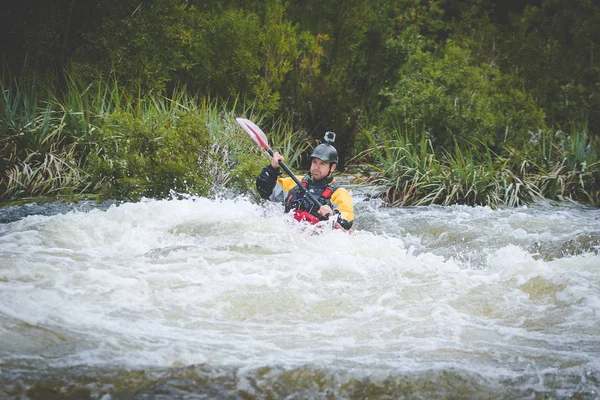 Close up image of a white water kayak paddler riding white water on a mountain river