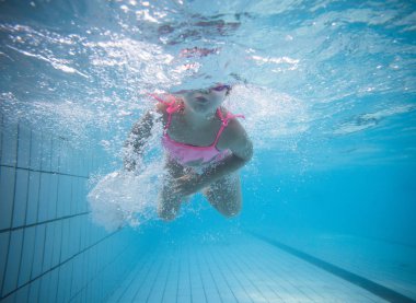 Geniş açı sualtı fotoğraf gözlük ve pembe bikini ile büyük bir yüzme havuzunda Yüzme bir yürümeye başlayan çocuk kız