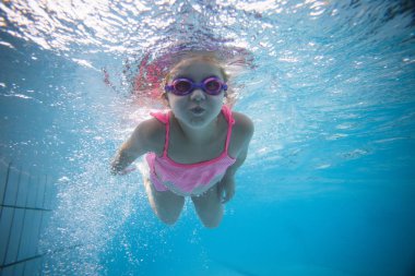 Geniş açı sualtı fotoğraf gözlük ve pembe bikini ile büyük bir yüzme havuzunda Yüzme bir yürümeye başlayan çocuk kız
