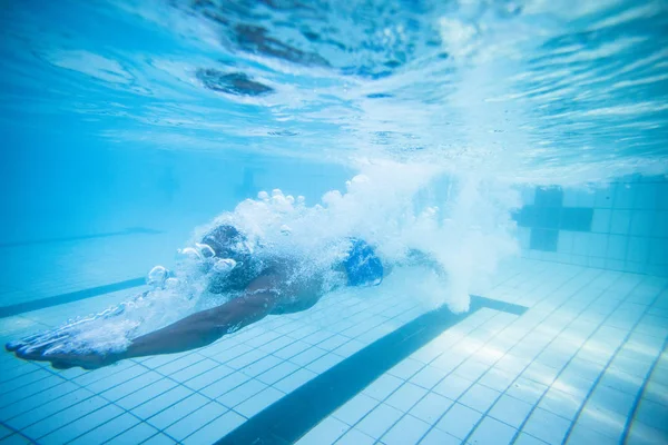 Underwater image of a male swimmer diving into an olympic swimming pool to train