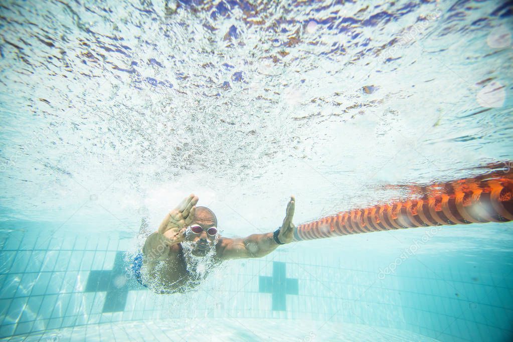 male swimmer diving and swimming in a swimming pool to train