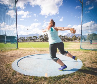 Disk atan bir kadın atletin geniş açılı aksiyon fotoğrafı.