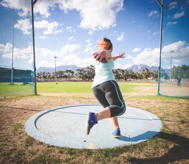 Disk atan bir kadın atletin geniş açılı aksiyon fotoğrafı.