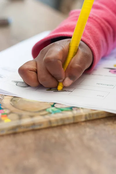 Close up image of a mixed race primary school learner writing in a workbook at school