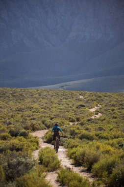 Dağ bisikletçisi bir dağ bisikletinde yokuş aşağı gidiyor.