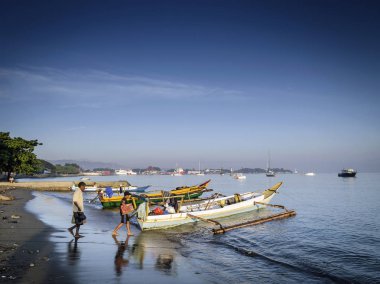 coast with traditional asian wooden longtail fishing boats on dili beach in east timor leste clipart