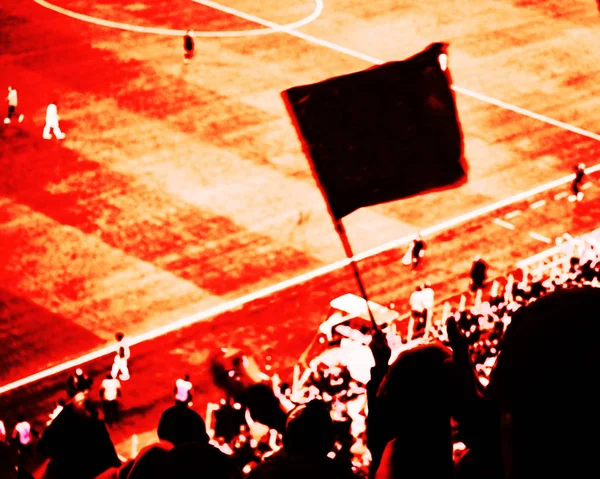 Футбольні фанати підбадьорюють свою футбольну команду забити гол з прапорами, банерами і шрафами на стадіоні. Червоно-чорний тонований вигляд — стокове фото