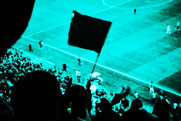Футбольні фанати підбадьорюють свою футбольну команду забити гол з прапорами, банерами і шрафами на стадіоні. Світло-блакитний тонований вид — стокове фото