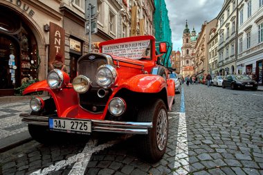 Prague, Çek Cumhuriyeti, 15 Eylül 2017: turistik vintage klasik kırmızı sıcak çubuk araba Charles Köprüsü (Karluv çoğu) Prag, Çek Cumhuriyeti için yakınlarında bir Arnavut kaldırımı yolda