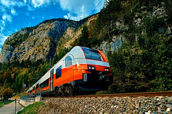 Kırmızı mavi tren hareket Avusturya Alplerinde dağlarda. Hallstatt Obertraun tren istasyonunda yüksek hızlı dağ Tren geldiğinde