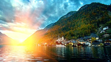 Hallstatt dağ tatil köyü ünlü kilise ile geleneksel alps evler ve ahşap kırsal tekne Hallstatt Gölü evler. Avusturya Alpleri dağlar üzerinde gündoğumu. Yer: Hallstatt, Avusturya, Alpler