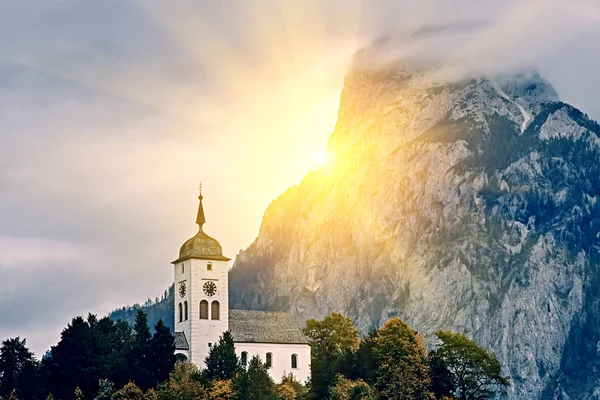 Hermosa puesta de sol panorámica sobre el lago de los Alpes austríacos. Iglesia en la roca con nubes sobre la montaña Traunstein en el lago de los Alpes cerca de Hallstatt Salzkammergut Austria — Foto de Stock