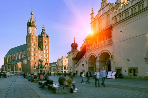Pazar Meydanı ve St Mary's Basilica günbatımı güneş ışığı çarpıcı Krakow, Polonya. Sokakta yürürken ve rahatlatıcı insanlar turist