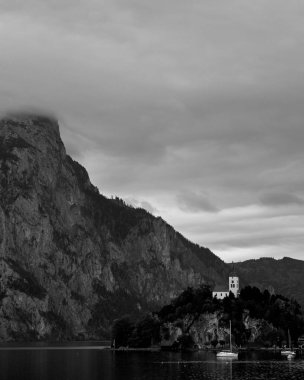 Avusturya Alplerinde Gölü üzerinden Vintage siyah beyaz görünüm. Tekneler, bulutlar üzerinde Traunstein Dağı'nda alps göl kenarında Hallstatt Salzkammergut Avusturya ile kayada kilise infront yatlar