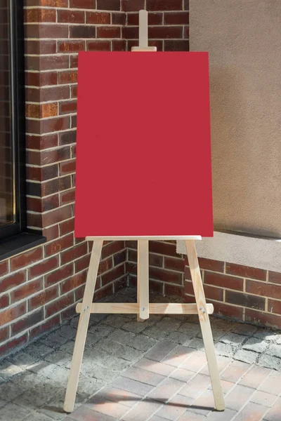 Träkonstnär staffli med röd blank mockup affisch för din design — Stockfoto