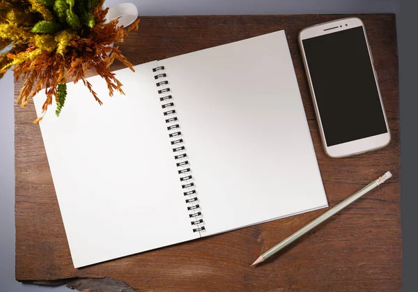 Boş defter kalem, smartphone ve beyaz fincan kahverengi ahşap masa arka plan üzerinde kuru çiçek ile.                              