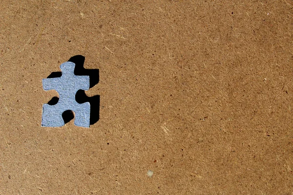 Izolowany Niebieski Karton Puzzle Kawałek Brązowym Drewnianym Tle — Zdjęcie stockowe