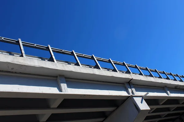 Concrete bridge with guard rail against blue sky