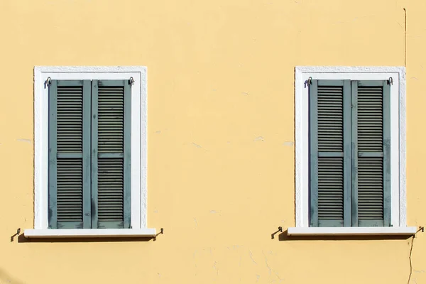 Closed shutter windows on a yellow building