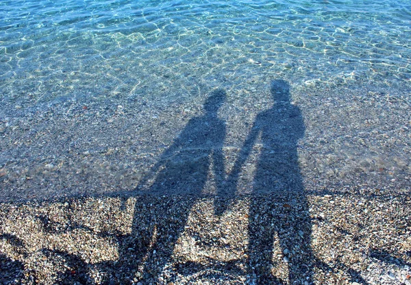 Men and woman shadows on water holding hands