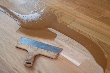 Ahşap tozu, odun cilası, sertleştirici ve diğer parke cilası karışımı, yerde spatula.