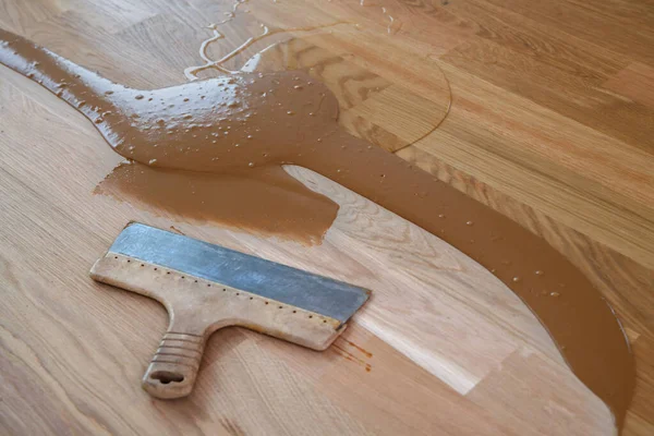 Ahşap tozu, odun cilası, sertleştirici ve diğer parke cilası karışımı, yerde spatula.