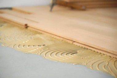 Yenilenmiş bir parke odasının inşaatı. Pad parke için yapıştırıcı ile uygulanır.    