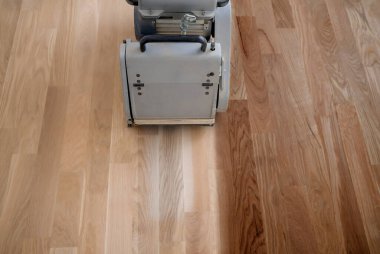 Öğütme makinesiyle ahşap zemini kazımak. Apartmanda tamirat var. Marangoz parke ahşap parke döşeme bakım işi yapıyor.