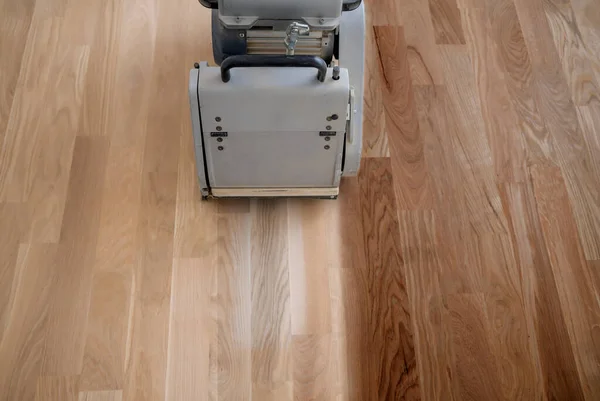 Öğütme makinesiyle ahşap zemini kazımak. Apartmanda tamirat var. Marangoz parke ahşap parke döşeme bakım işi yapıyor.