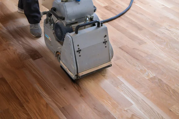 用磨床擦拭硬木地板 在公寓里修理 木匠用磨床做木地板抛光维护工作 — 图库照片