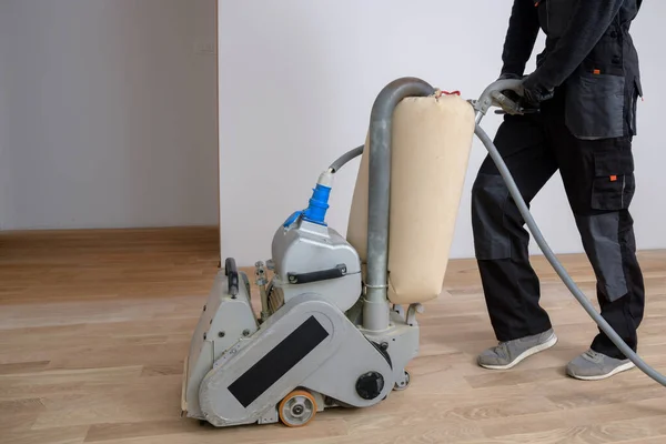 Öğütme makinesiyle ahşap zemini kazımak. Apartmanda tamirat var. Marangoz parke ahşap parke döşeme bakım işi yapıyor.