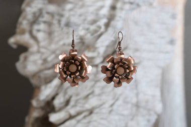 Beyaz taşın üzerinde el yapımı çiçek şeklinde klasik Cooper küpeleri.