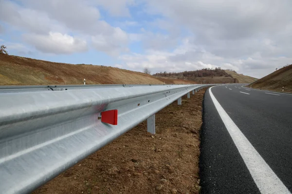 Steel guard rail barrier on the motorway with reflective red sign