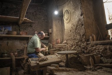 Erkek çömlekçi çömlek çarkında demlik yapıyor. Terracotta çömlekçi çocuk. Arazi merkezi olan çömlekçilik hakkında fikir üreten adamlar.
