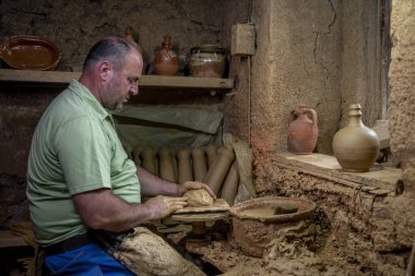 Erkek çömlekçi çömlek çarkında demlik yapıyor. Terracotta çömlekçi çocuk. Arazi merkezi olan çömlekçilik hakkında fikir üreten adamlar.