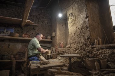Erkek çömlekçi çömlek çarkında demlik yapıyor. Terracotta çömlekçi çocuk. Arazi merkezi olan çömlekçilik hakkında fikir üreten adamlar.