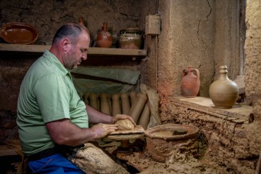 Erkek çömlekçi çömlek çarkında demlik yapıyor. Terracotta çömlekçi çocuk. Arazi merkezi olan çömlekçilik hakkında fikir üreten adamlar.