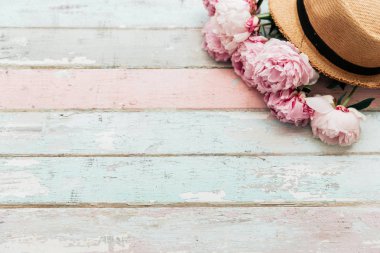 Güzel şakayık çiçekleri ve ışık mavi ahşap plakalar arka plan üzerinde hasır şapka