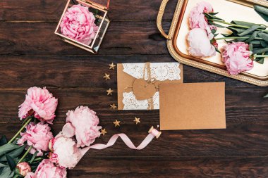 Güzel pembe peonies koyu ahşap masa üzerinde altın tepsi ile boş boş oyun kağıdı
