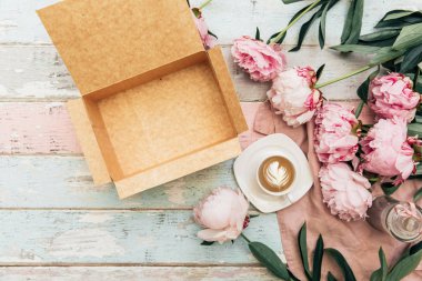 ahşap masa üzerinde peonies, fincan kahve ve boş kağıt kutusu üstten görünüm