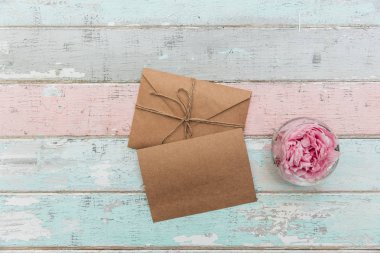 Şakayık Çiçeği cam ve ahşap masanın üzerine düzenlenmiş boş kağıt zarflar üstten görünüm