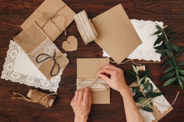 Düz araçları DIY ahşap bir masa üzerinde yatıyordu: kağıt, makas, iplik, zeytin dalı. Kendi kendine yapılan zarf harfler için. Üstten görünüm.