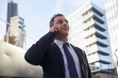 Kentsel çevrede cep telefonuyla konuşan iş adamı