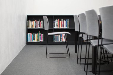 Beyaz ortamda arka planda bir kitaplık ile kütüphanede Sandalyeler