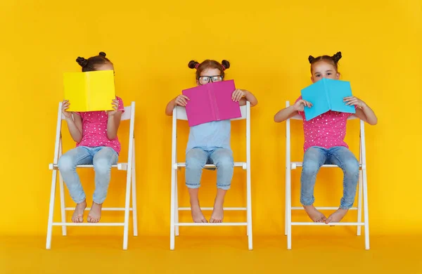 滑稽的孩子女孩读书在色的黄色背景 — 图库照片