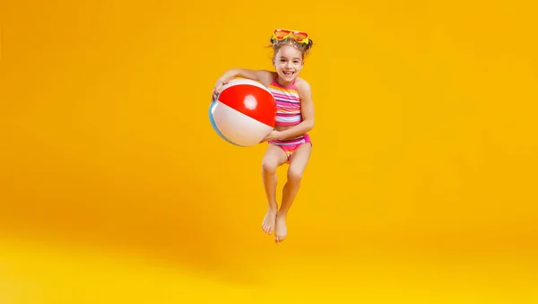 水着とスイミング グラス着色された背景があるジャンプ面白い幸せな子 — ストック写真