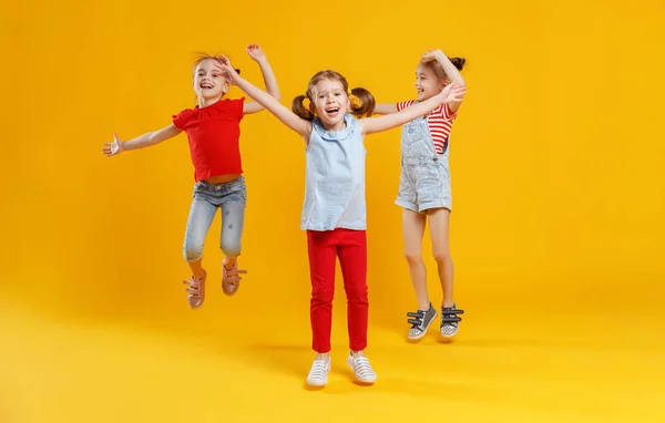 Grappige Kinderen Meisjes Springen Een Gekleurde Gele Pagina — Stockfoto